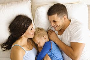 Eltern und Kind kuscheln im Bett
