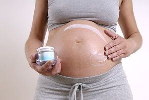 Schwangere cremt sich den Bauch ein