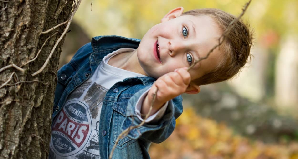 6-jähriger Junge hält dünnen Zweig in der Hand und lacht