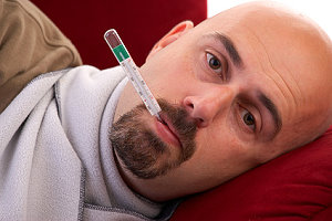 Mann mit Fieberthermometer im Mund