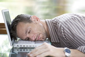 Mann schläft auf seinem Laptop
