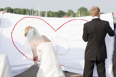 Brautpaar schneidet Herz aus einem Bettlaken