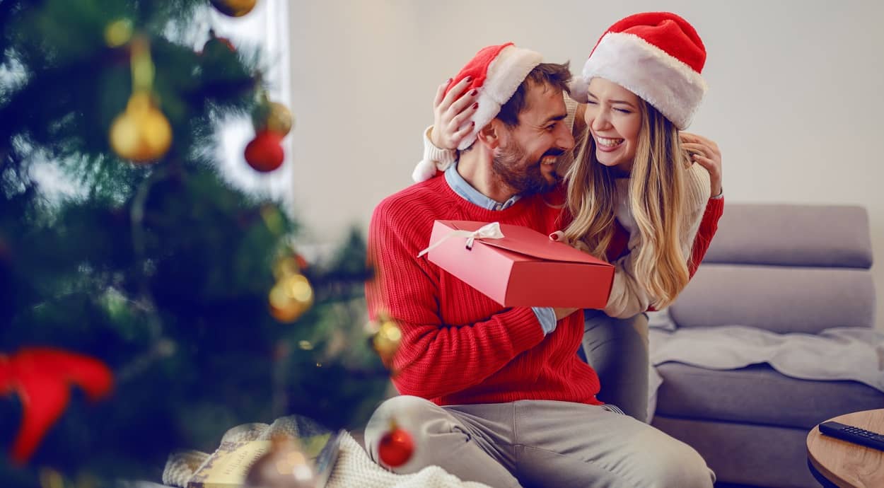 Frau überreicht ihrem Mann ein Weihnachtsgeschenk