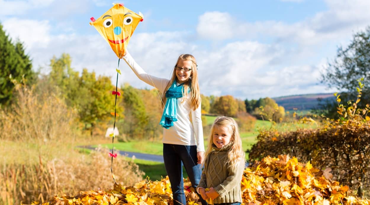 Kinder lassen in den Herbst Ferien einen Drachen steigen