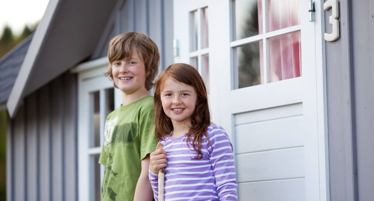 Zwei Kinder vor einem Ferienhaus