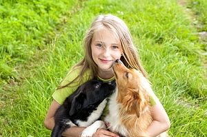 Mädchen kuschelt mit zwei Hunden