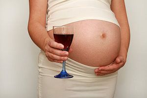 Eine Schwangere hält ein Glas Rotwein in der Hand
