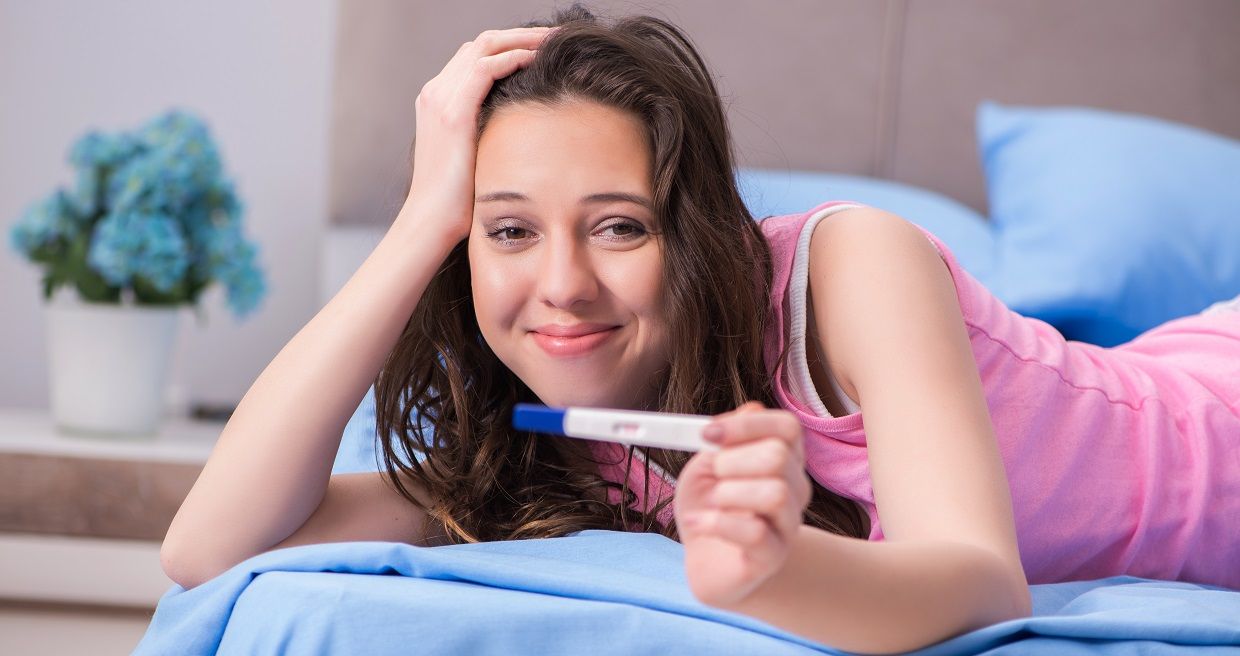 Junge Frau in den ersten Schwangerschaftswochen mit einem Schwangerschaftstest