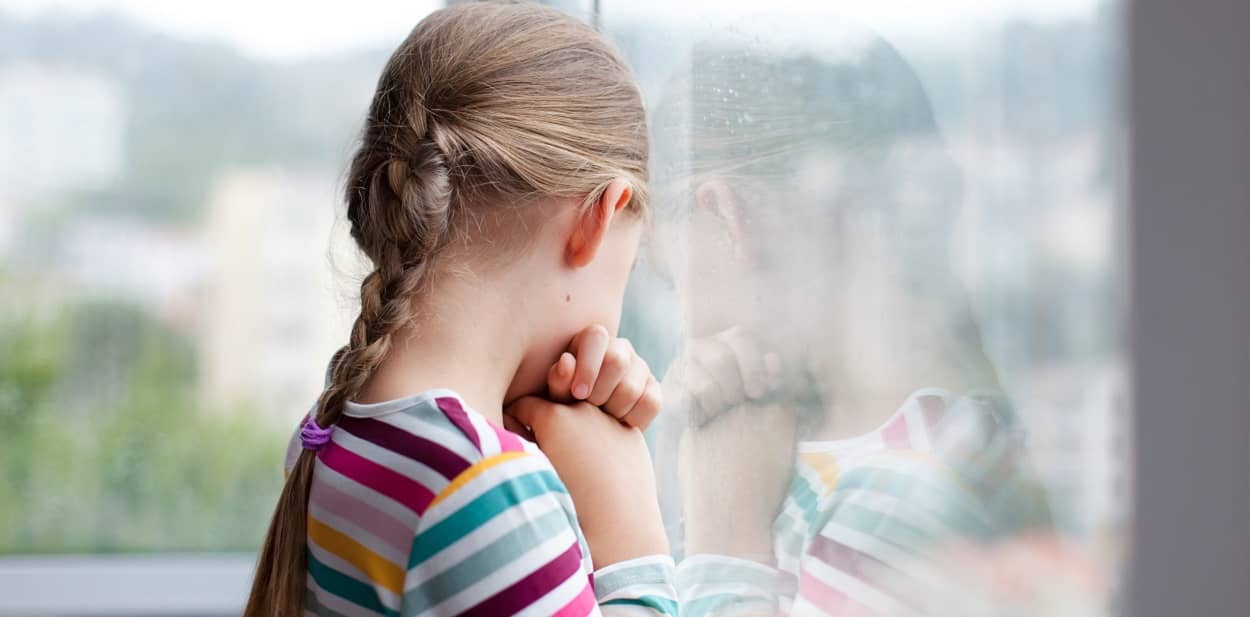 Mädchen schaut aus dem Fenster und hat Angst vor den anderen Kindern