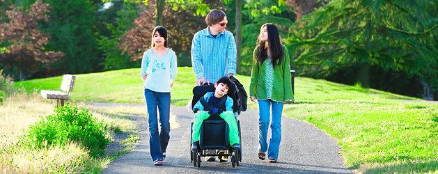Behinderter Junge mit seiner Familie beim Spaziergang