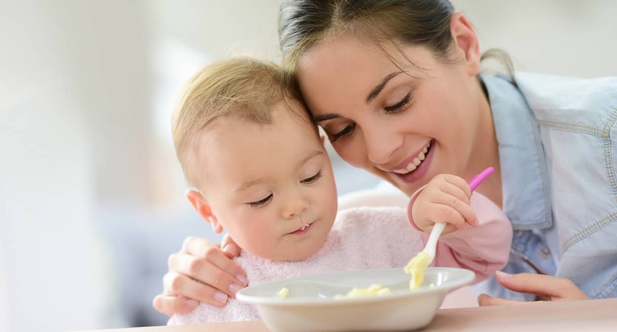 Mama füttert Baby mit Brei
