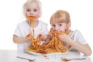 Zwei Mädchen essen Spaghetti mit den Fingern