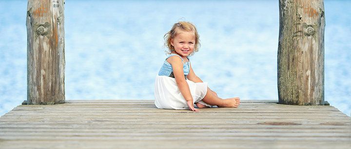 Kleines Mädchen sitzt wartend auf einem Steg
