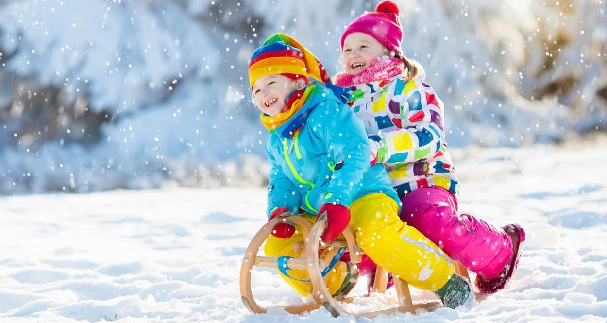 Kinder haben Spaß im Schnee mit dem Schlitten