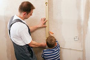 Vater und Sohn vermessen eine Wand